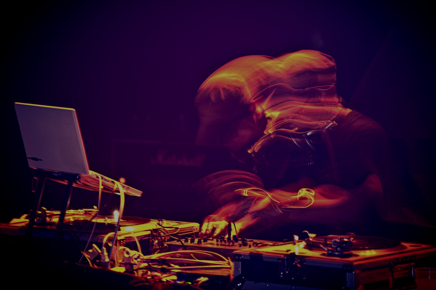 Las manos de un DJ en la mesa de mezclas bajo luz morada